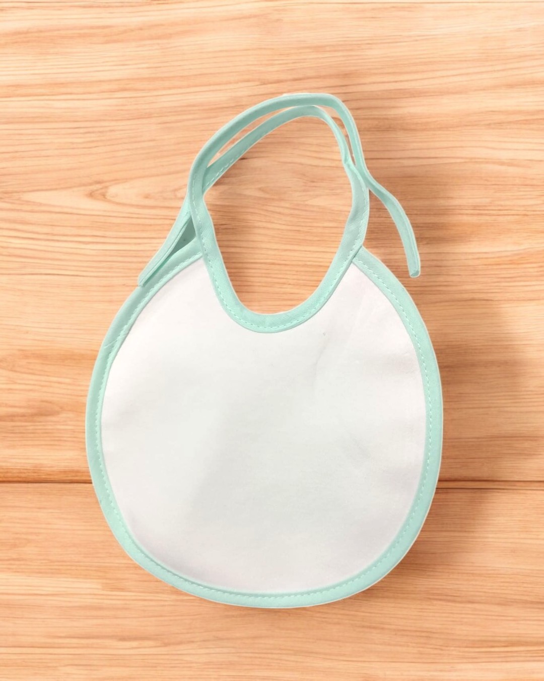 Babete branco com borda azul clara sobre madeira