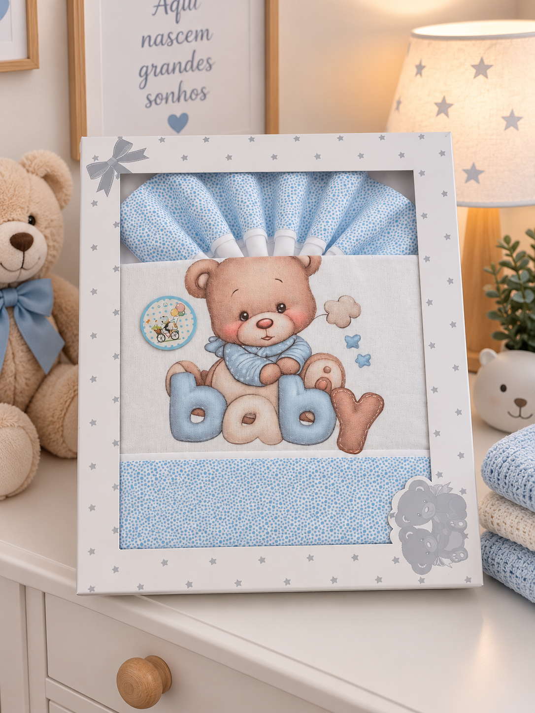 Conjunto de roupa de bebé azul com urso bordado e palavra baby numa caixa branca com estrelas cinzentas