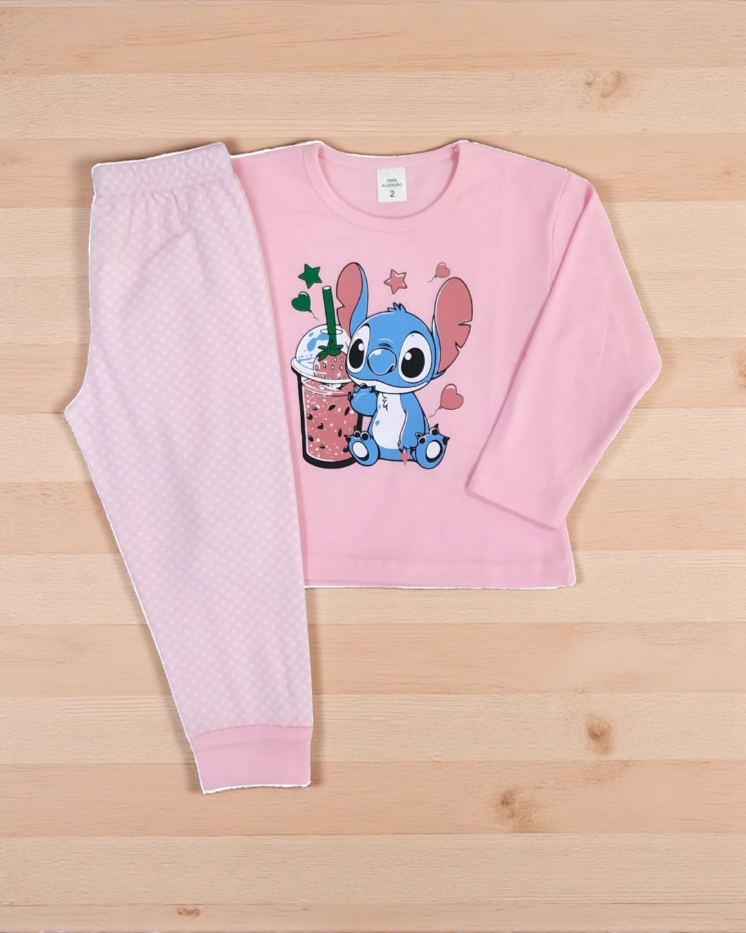 Pijama infantil rosa com estampa de Stitch e bebida em fundo claro