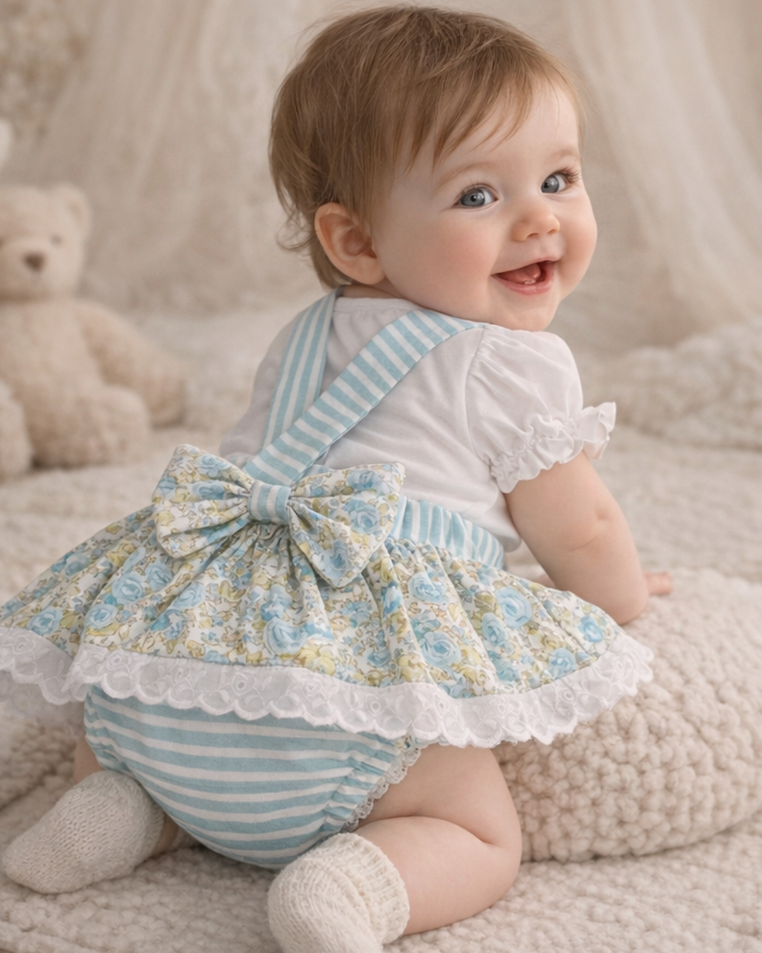 Bebé sorridente de vestido floral azul com laço e meias brancas, em ambiente interior acolhedor
