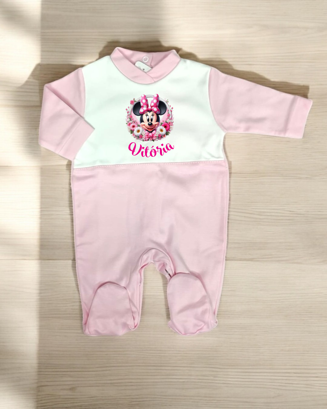 Macacão de bebé rosa claro com parte superior branca e imagem da Minnie Mouse com o nome 'Vitória' no peito