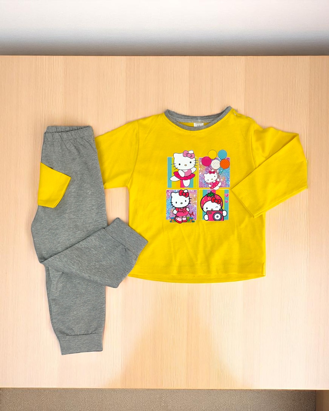 Pijama infantil amarelo e cinza com personagens animados na camisola e calças com patches amarelos