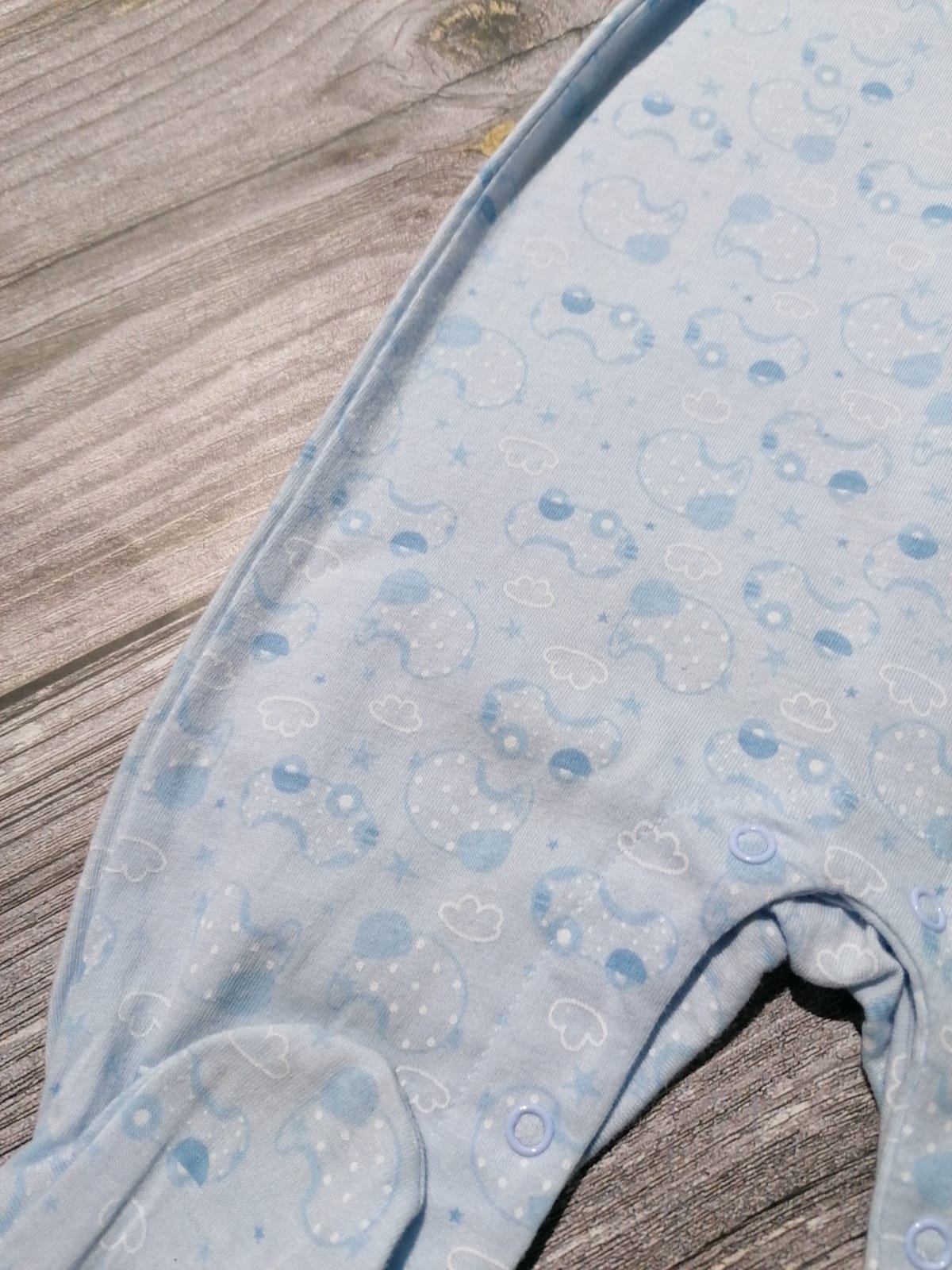 Pijama azul claro com padrão de nuvens e botões de pressão sobre madeira clara