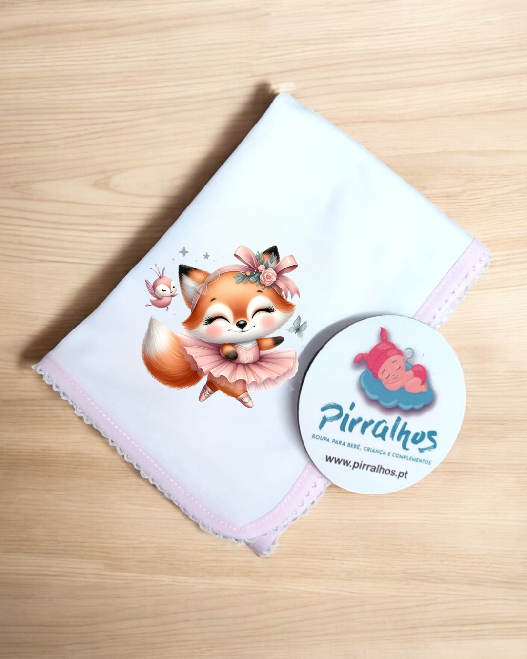 Fralda branca com raposa rosa dobrada sobre superfície de madeira clara