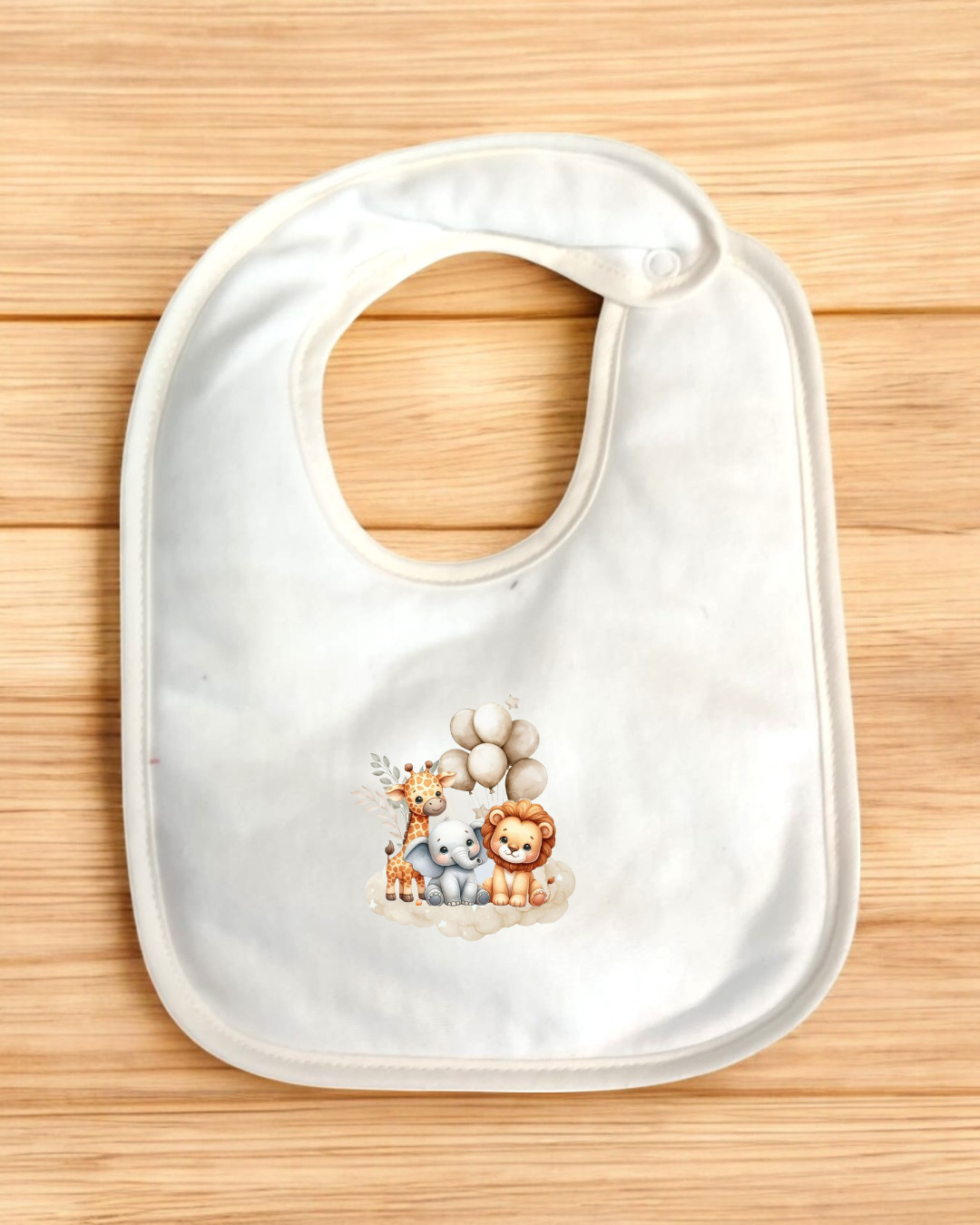 Babete branco com estampa de animais e balões sobre superfície de madeira