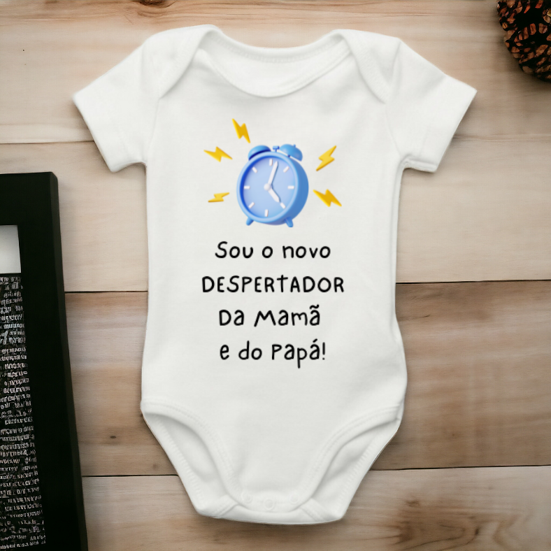 Body de bebé branco com estampa de relógio e texto em português sobre superfície de madeira