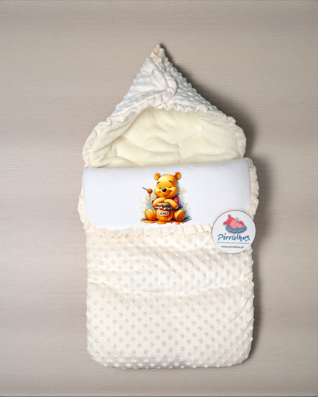 Saco de bebé cor creme com estampa do ursinho Pooh sobre fundo bege