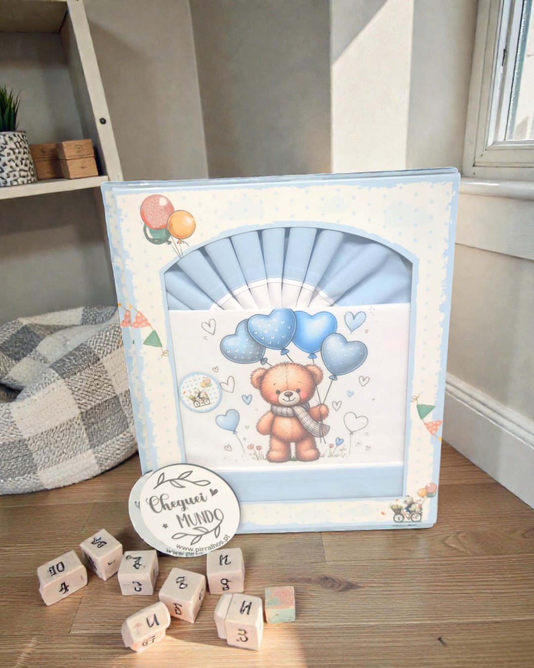 Caixa azul com ursinho e cubos de madeira com letras e números no chão de madeira