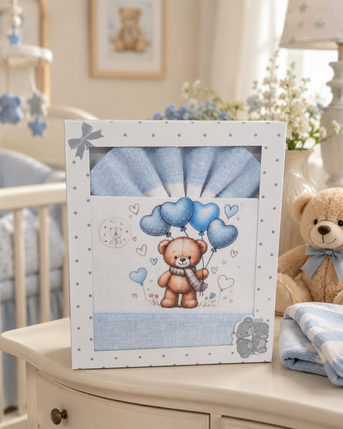 Conjunto de bebé azul com ursinho e balões em caixa branca decorada com estrelas cinzentas