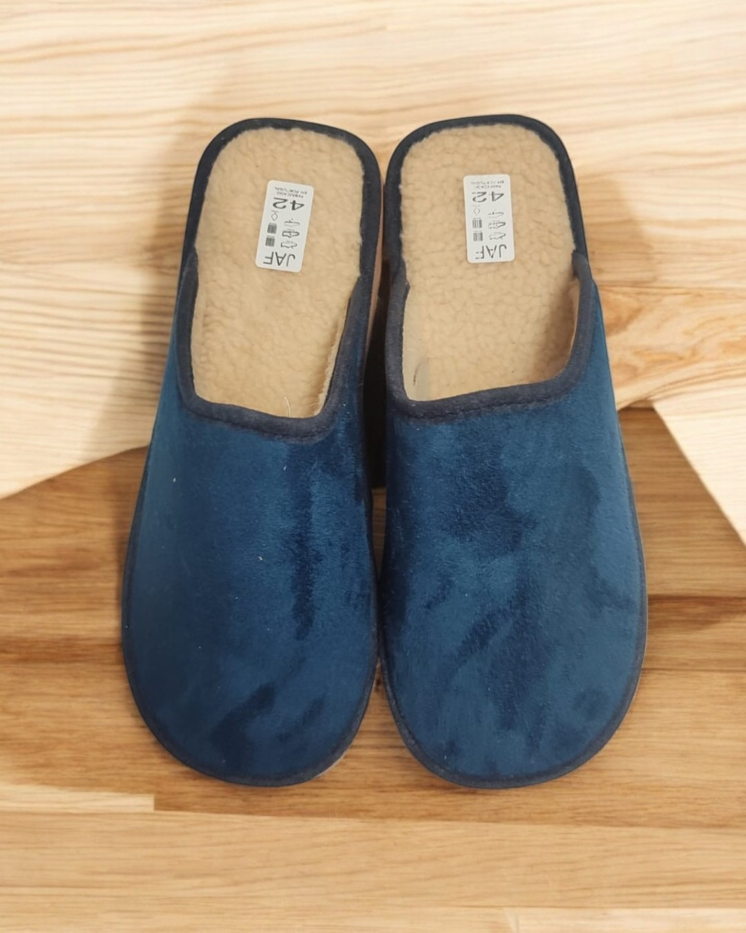 Chinelos azuis com interior de pelo sintético sobre madeira clara