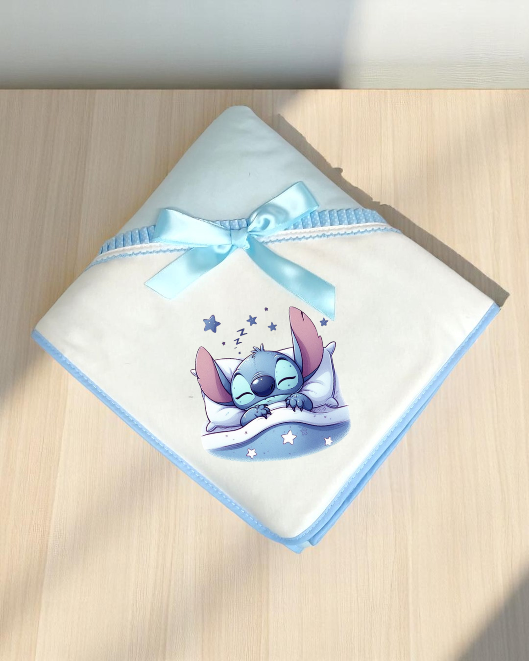 Manta branca com bordas azuis e desenho do Stitch a dormir