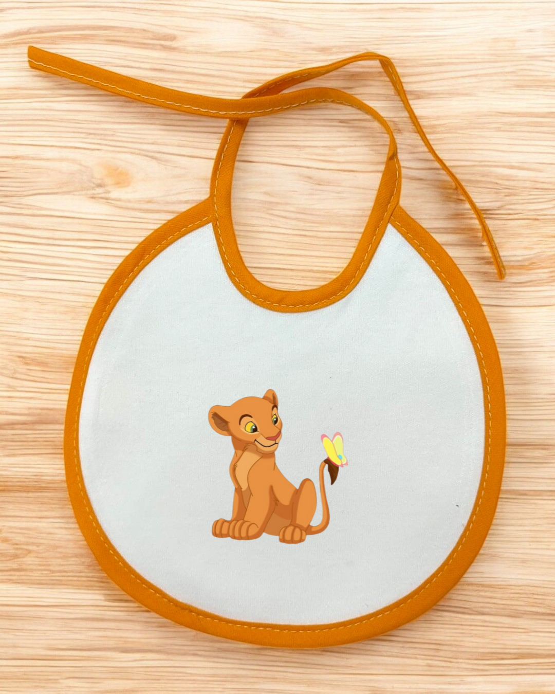 Babete branco com bordas alaranjadas e estampa do Simba com borboleta.