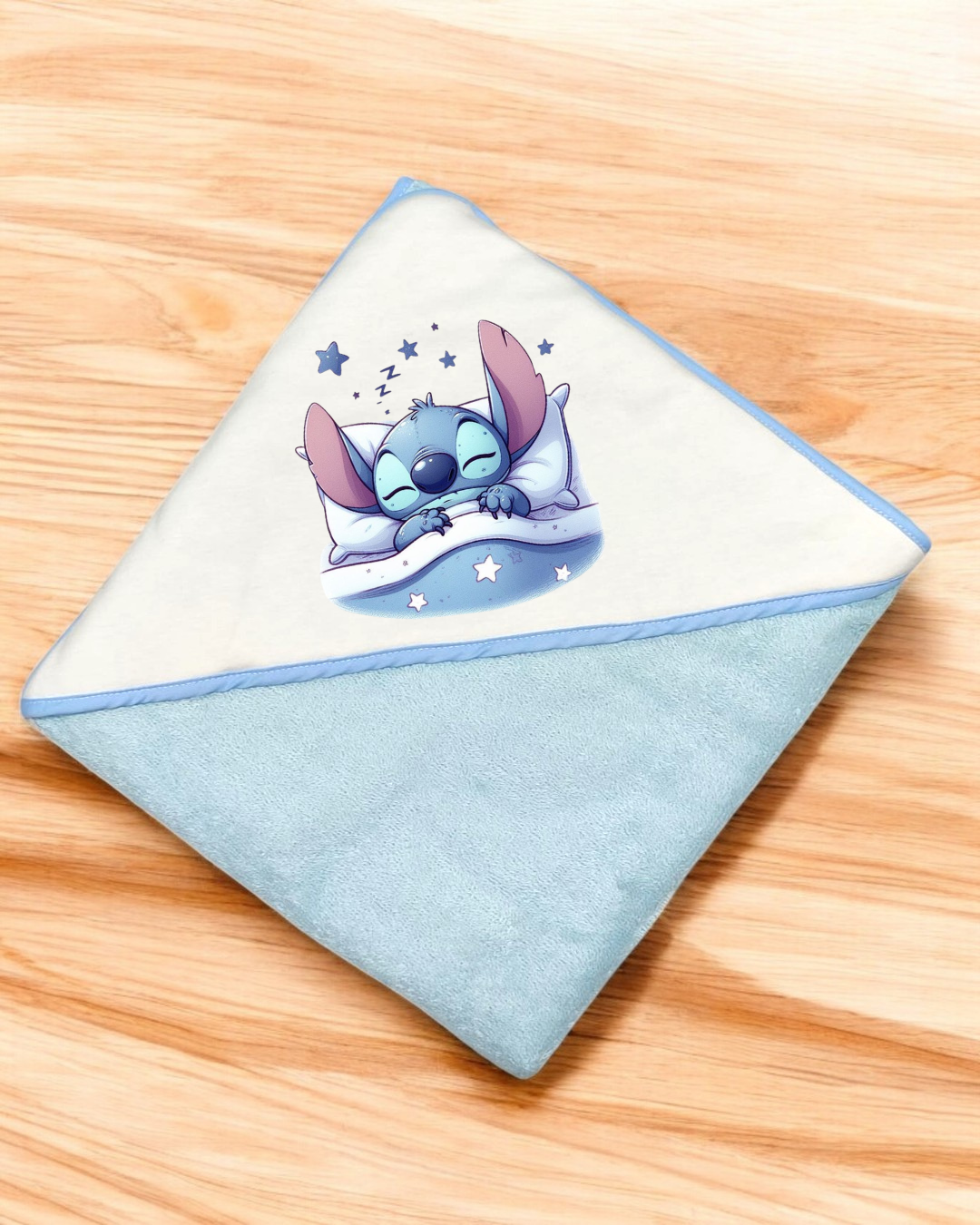 Fralda ou toalha de bebé azul claro com personagem azul a dormir e estrelas