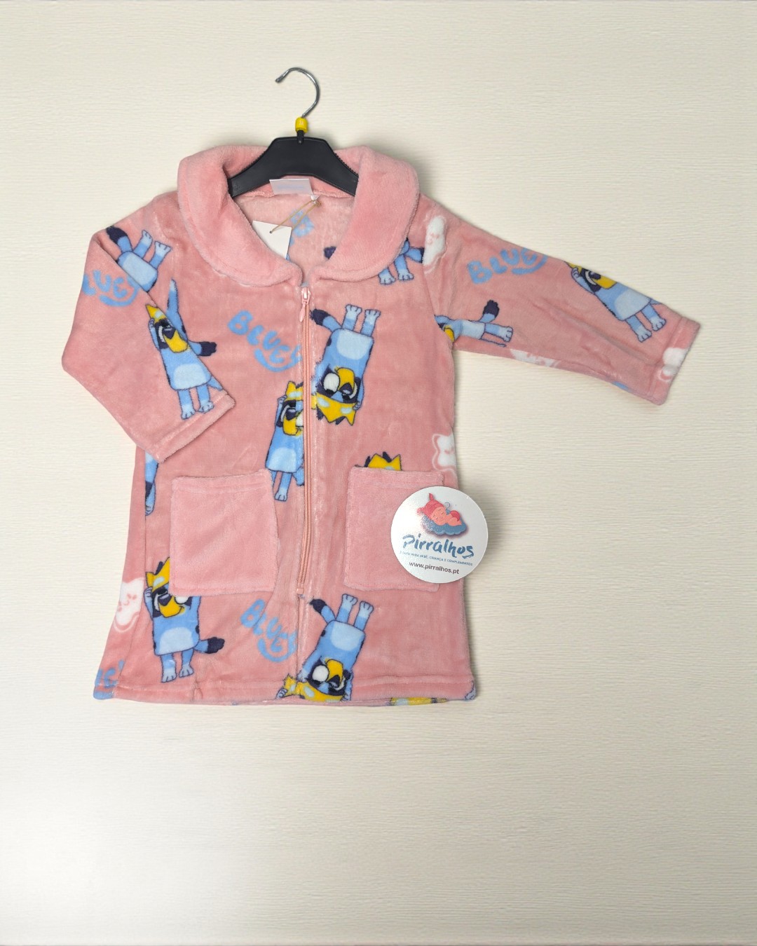 Robe infantil cor-de-rosa com desenhos azuis e amarelos e etiqueta Pirralhos