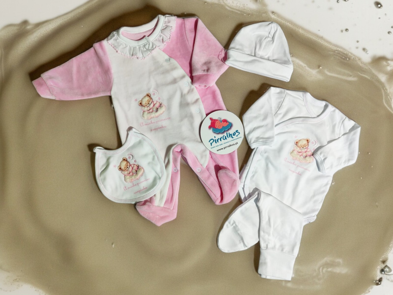 Conjunto de roupa de bebé rosa e branco com estampas de ursinhos sobre fundo bege texturizado