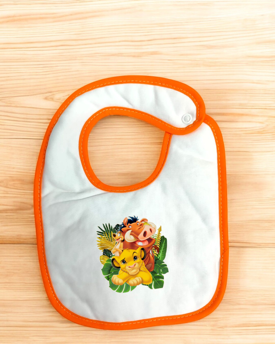 Babete branco com contorno laranja e desenho do Rei Leão