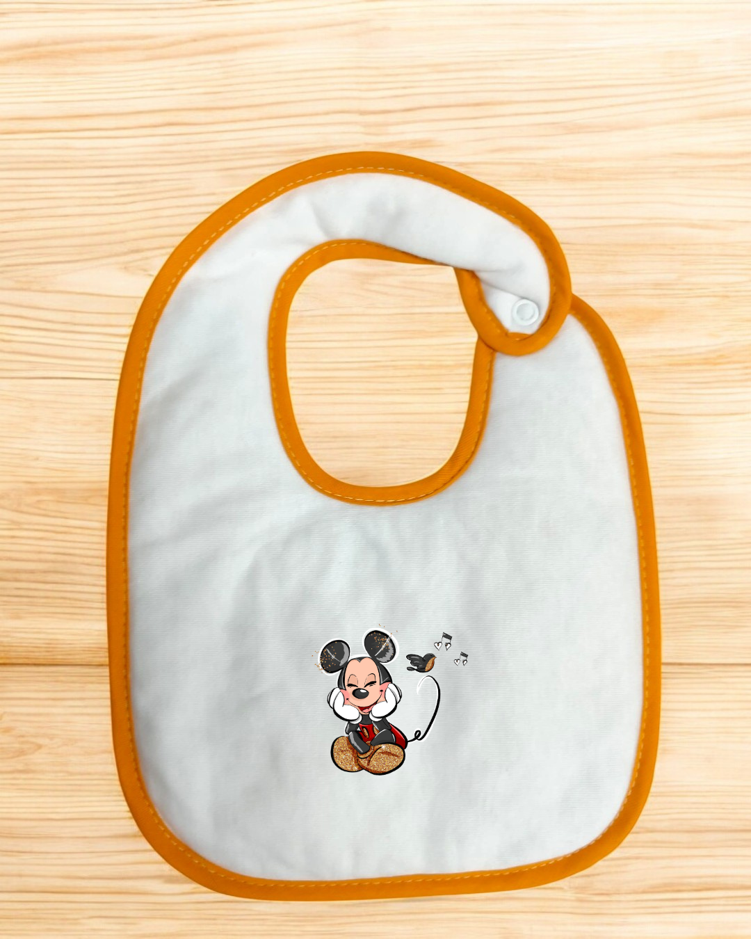 Babete branco com bordas laranja e estampa de personagem tipo Mickey Mouse sentado