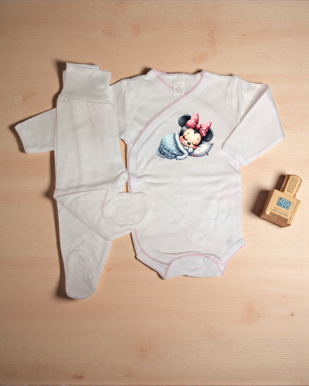 Conjunto de roupa de bebé branca com body e calças, body com imagem da Minnie a dormir e laço cor-de-rosa