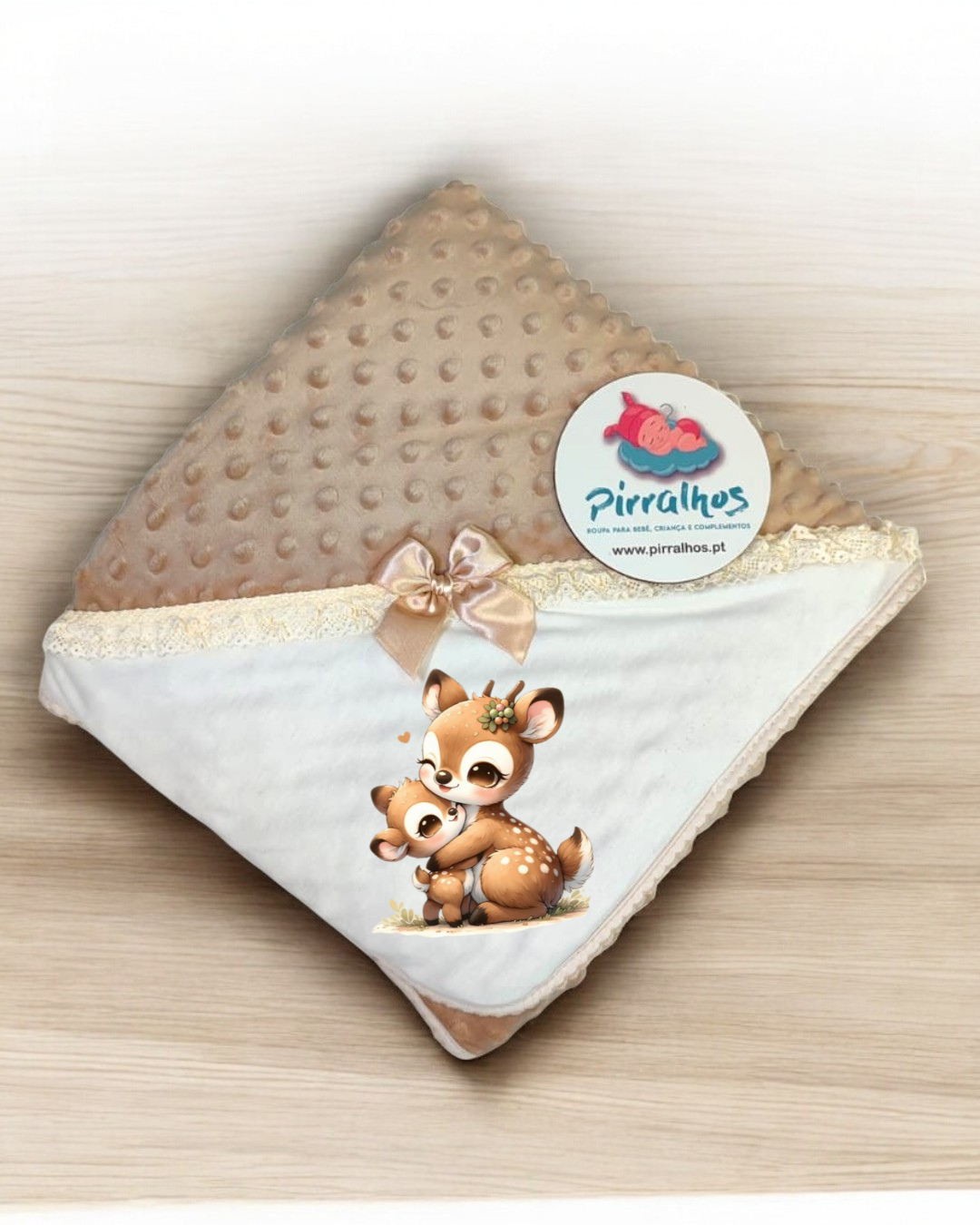 Manta de bebé bege e branca com ilustração de veados e etiqueta da marca Pirralhos