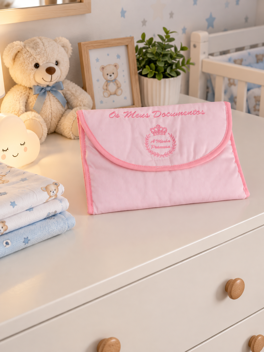 Bolsa rosa de tecido para documentos numa cómoda branca com decoração infantil de ursinho e plantas