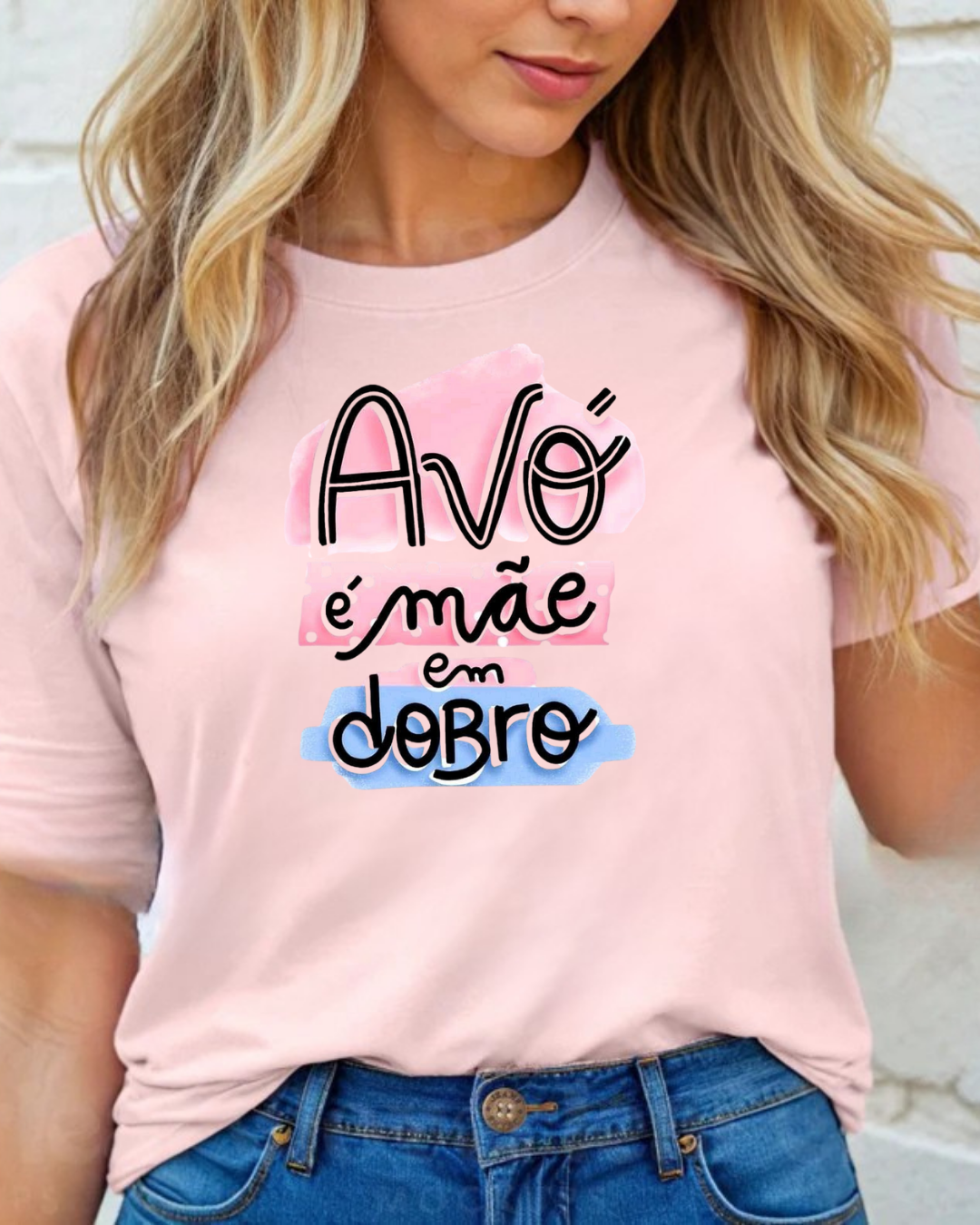 T-shirt rosa com texto colorido 'Avó é mãe em dobro', vista de mulher com jeans