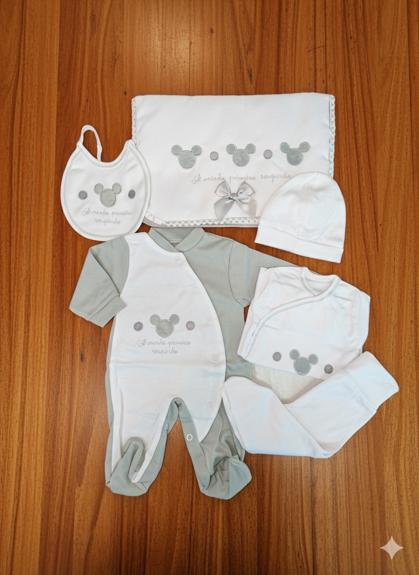 Conjunto de roupa de bebé branco e cinzento com padrão de cabeça de rato e texto, em superfície de madeira.