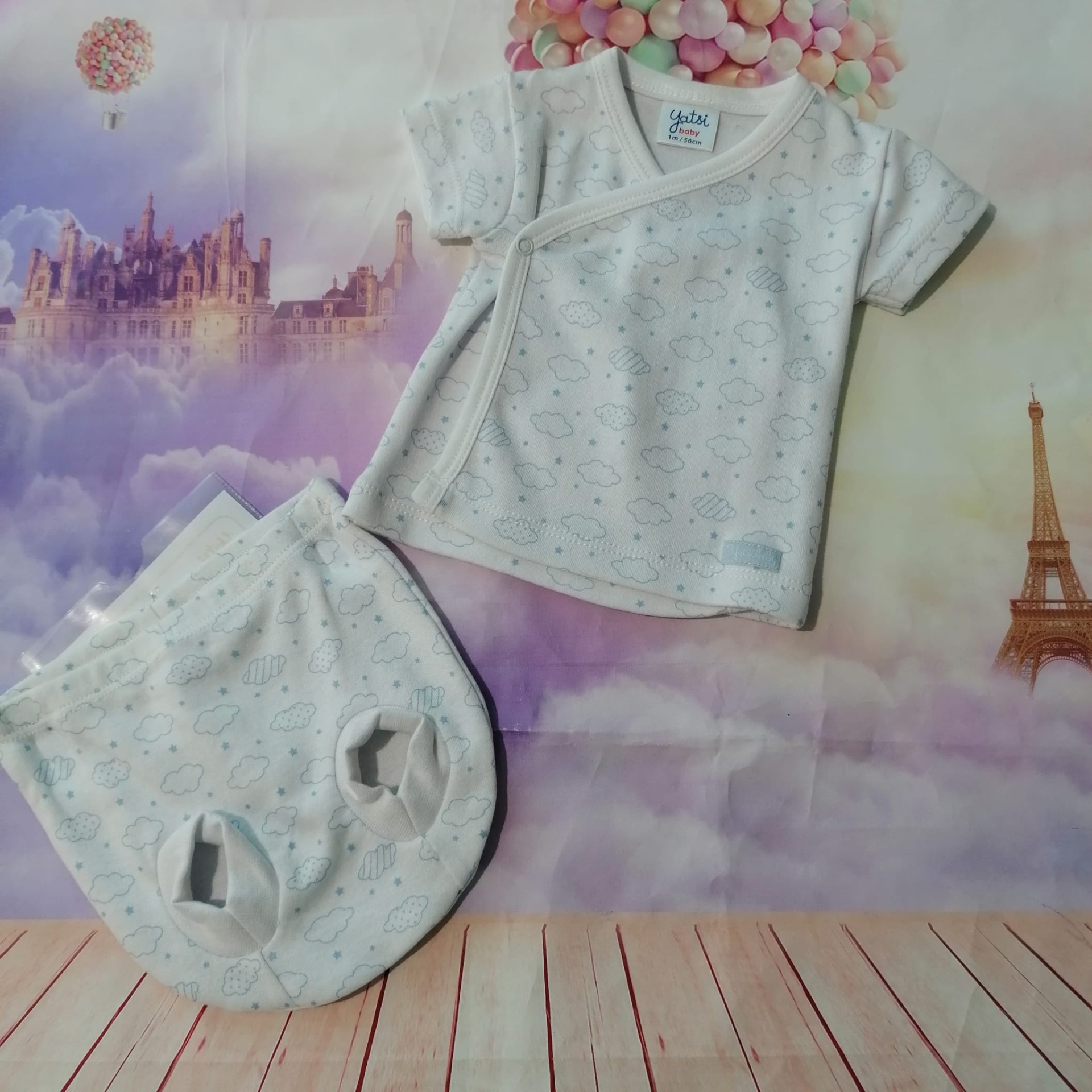 Conjunto de roupa de bebé branca com padrão de peixes azuis.