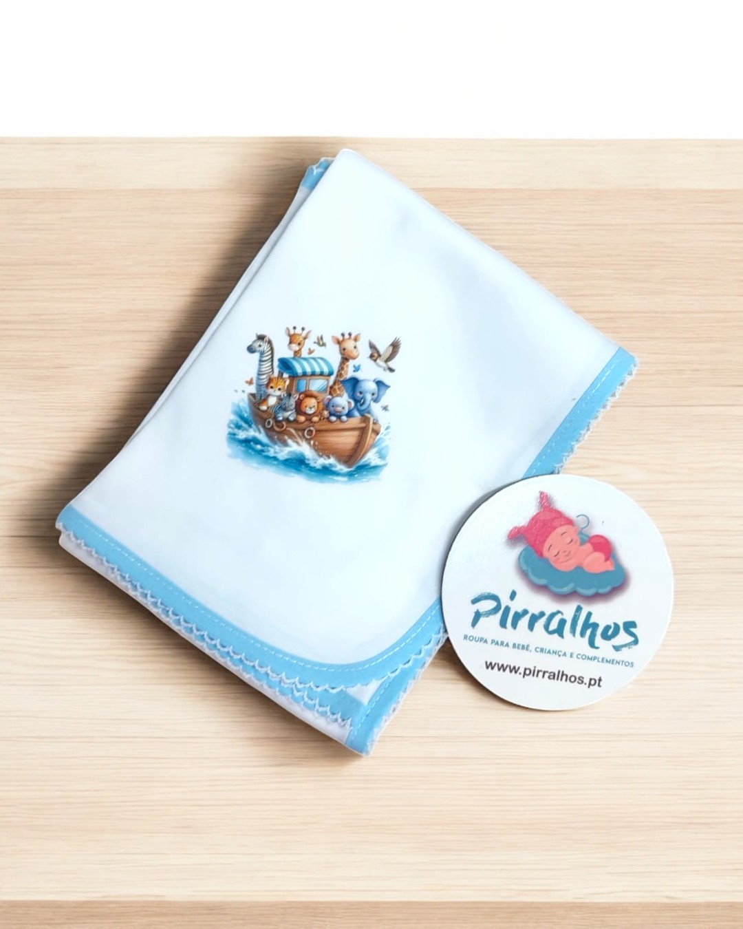 Cueiro branco com borda azul e ilustração de barco com animais, com etiqueta Pirralhos.