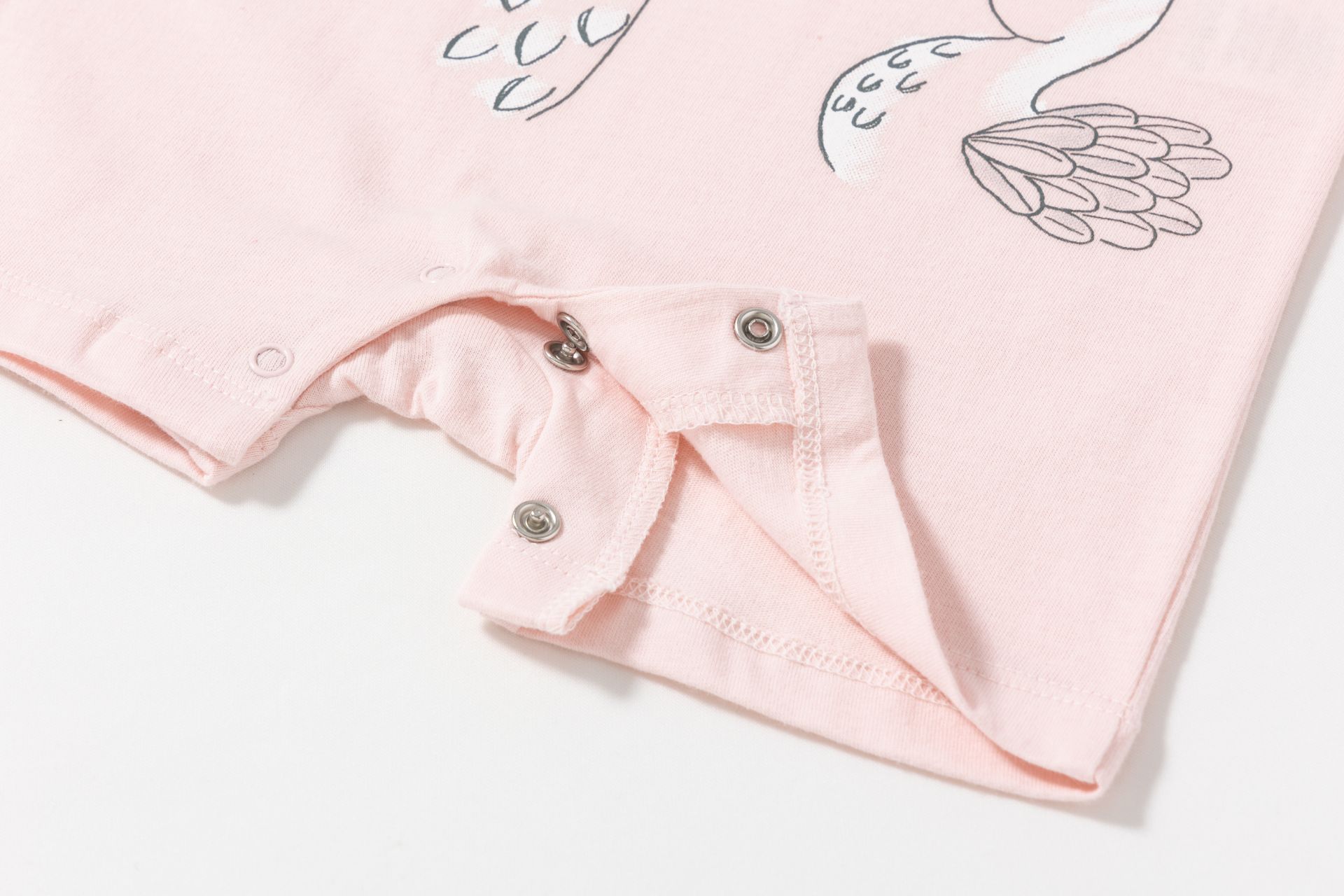 Roupa infantil rosa claro com fechos metálicos e estampa de penas