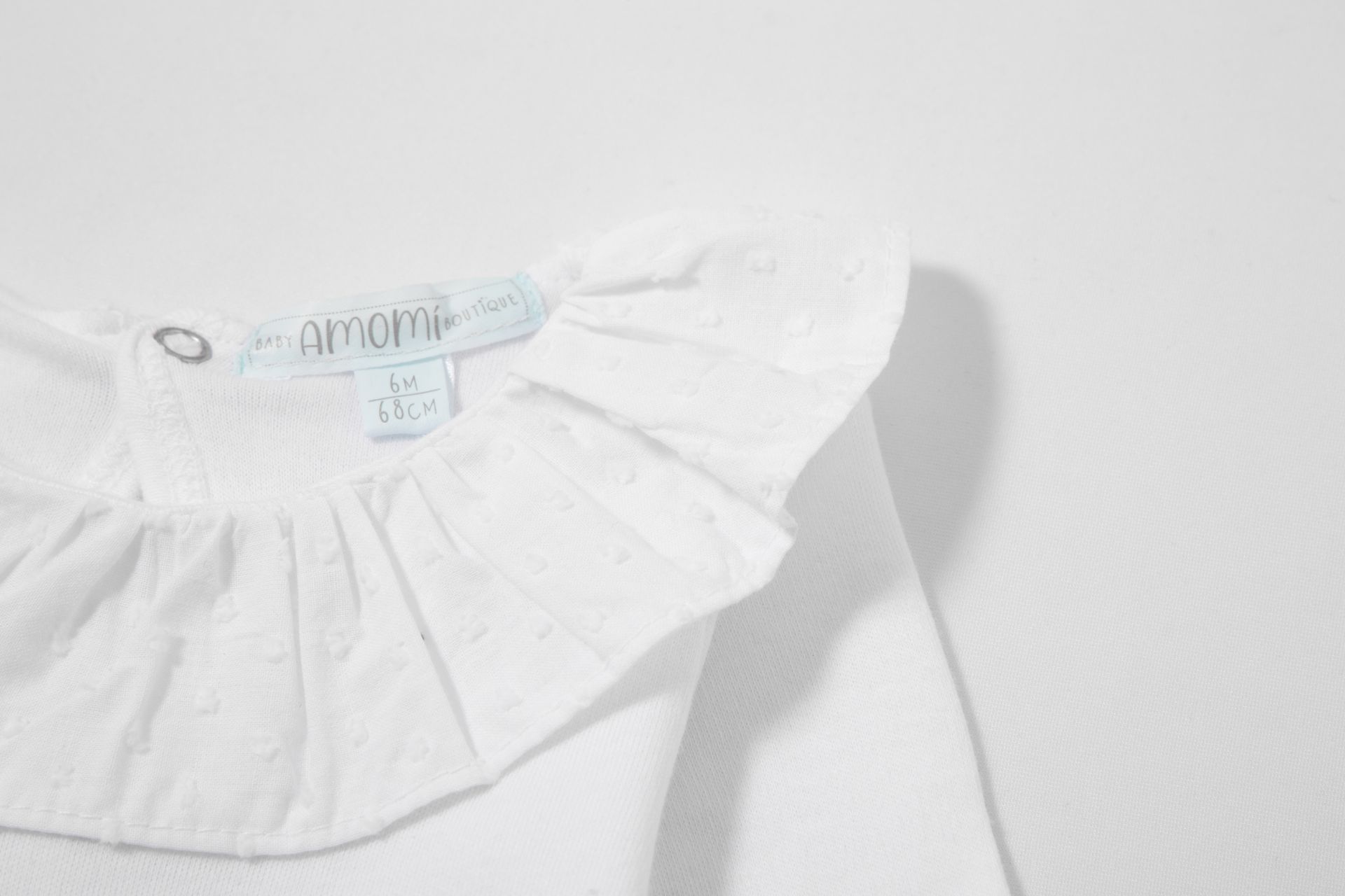 Blusa infantil branca com gola franzida e etiqueta interna AMIAMI