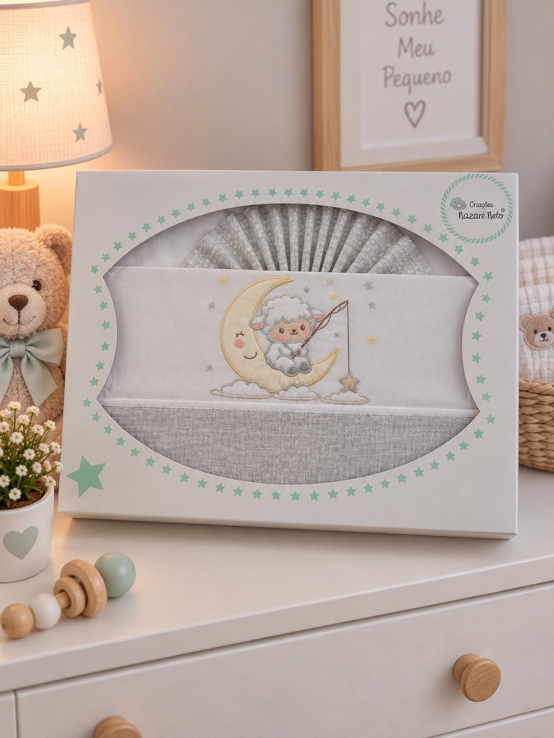 Conjunto de roupa de bebé com bordado de cordeirinho num quadro de lua, em embalagem decorada com estrelas verdes