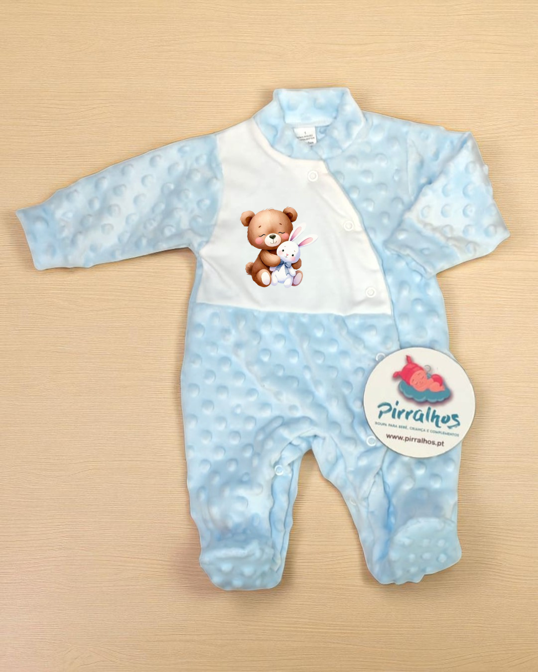Macacão azul claro para bébé com estampa de ursinho e coelho e etiqueta da marca Pirralhos