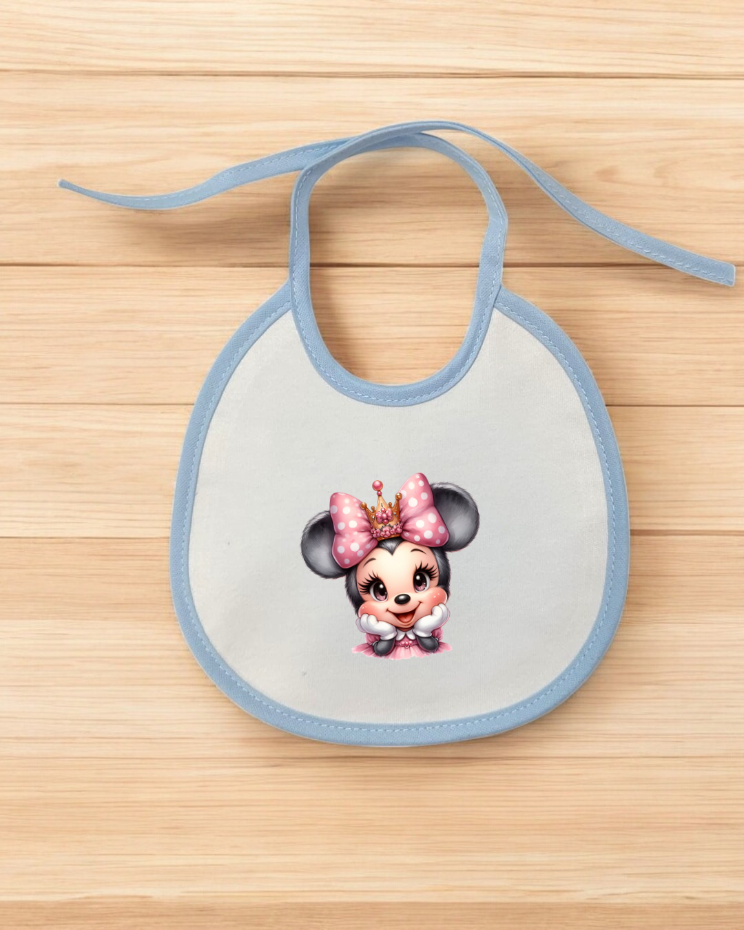 Babete branco com bordas azuis e personagem com laço rosa e coroa