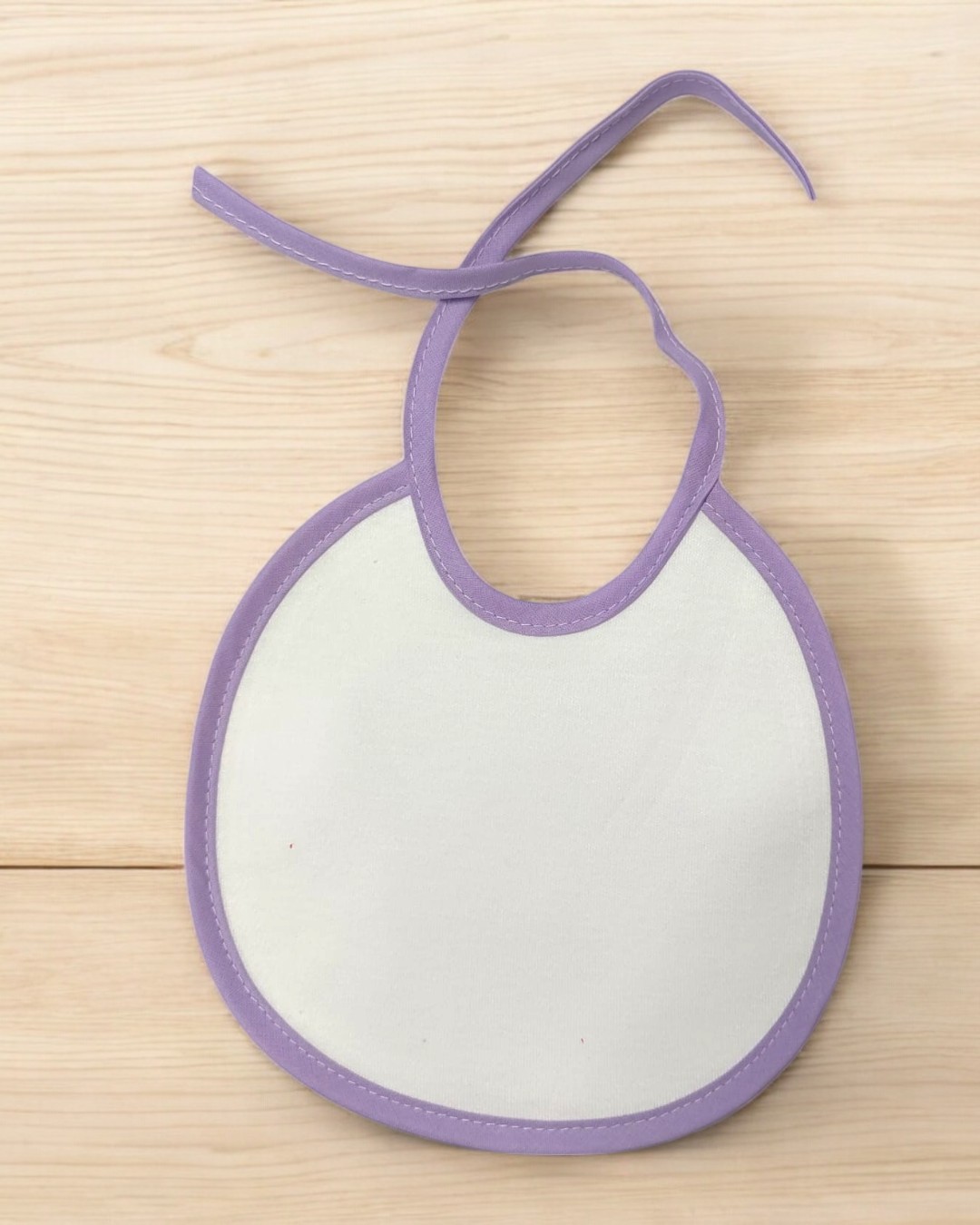 Babete branco com borda lilás sobre madeira clara