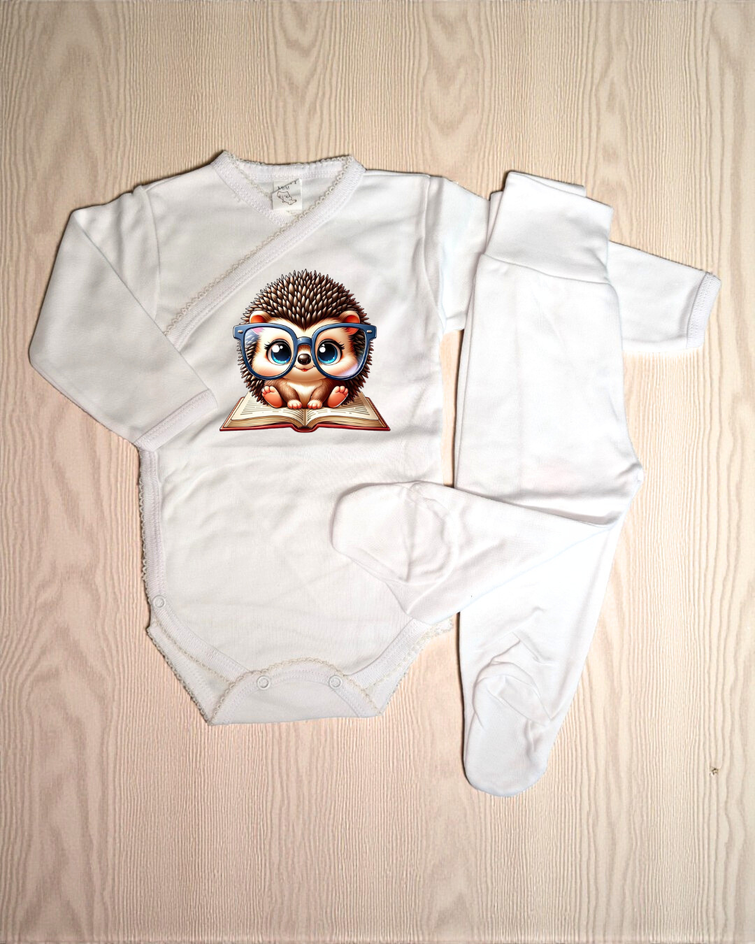 Conjunto branco de bebé com ouriço e óculos azuis a ler livro.
