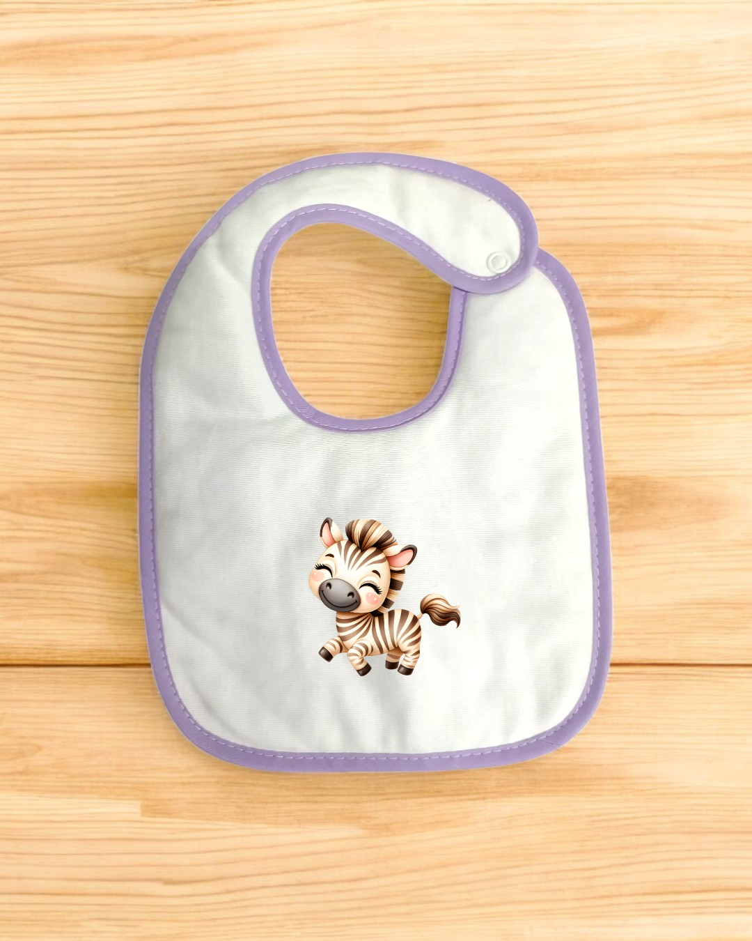 Babete branco com borda lilás e ilustração de zebra sobre superfície de madeira