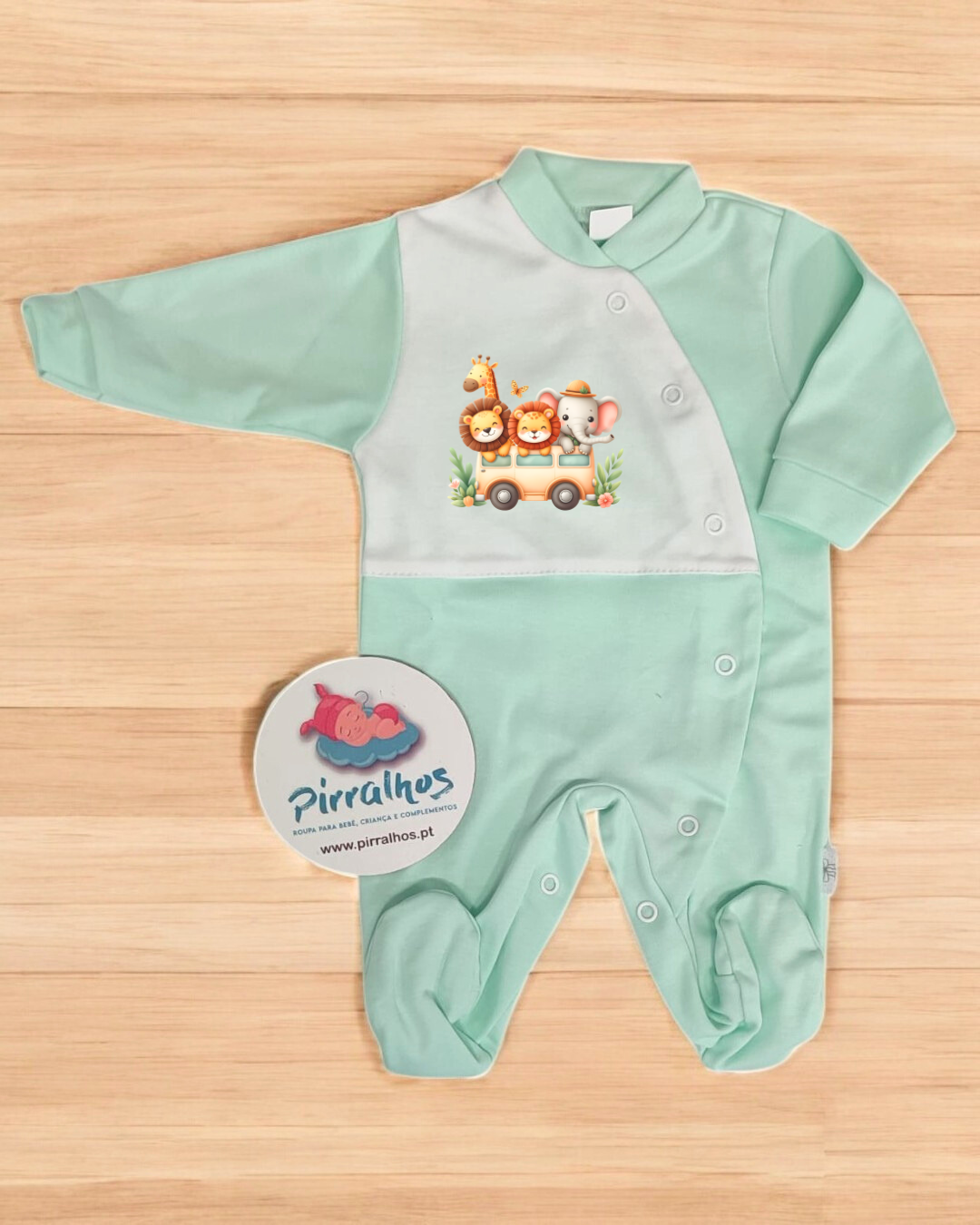Macacão de bebé verde com estampado de animais em autocarro sobre superfície de madeira