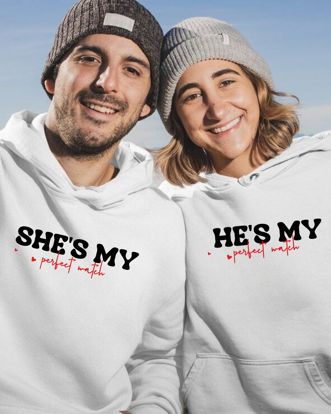 Casal com sweatshirts brancas e gorros de malha sorrindo ao ar livre