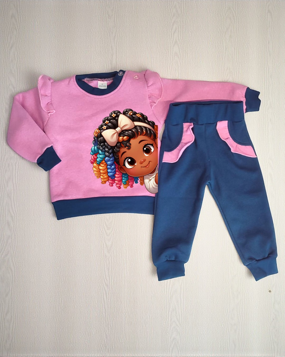 Conjunto infantil rosa e azul com estampa de menina e calças confortáveis.