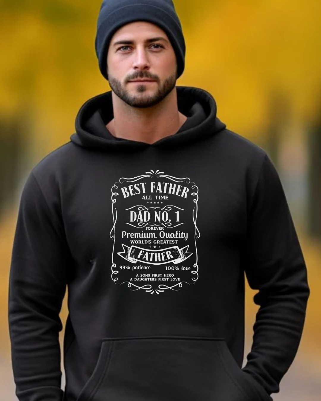 Homem de gorro preto usando camisola preta com capuz e estampa branca sobre paternidade em fundo com árvores amarelas.