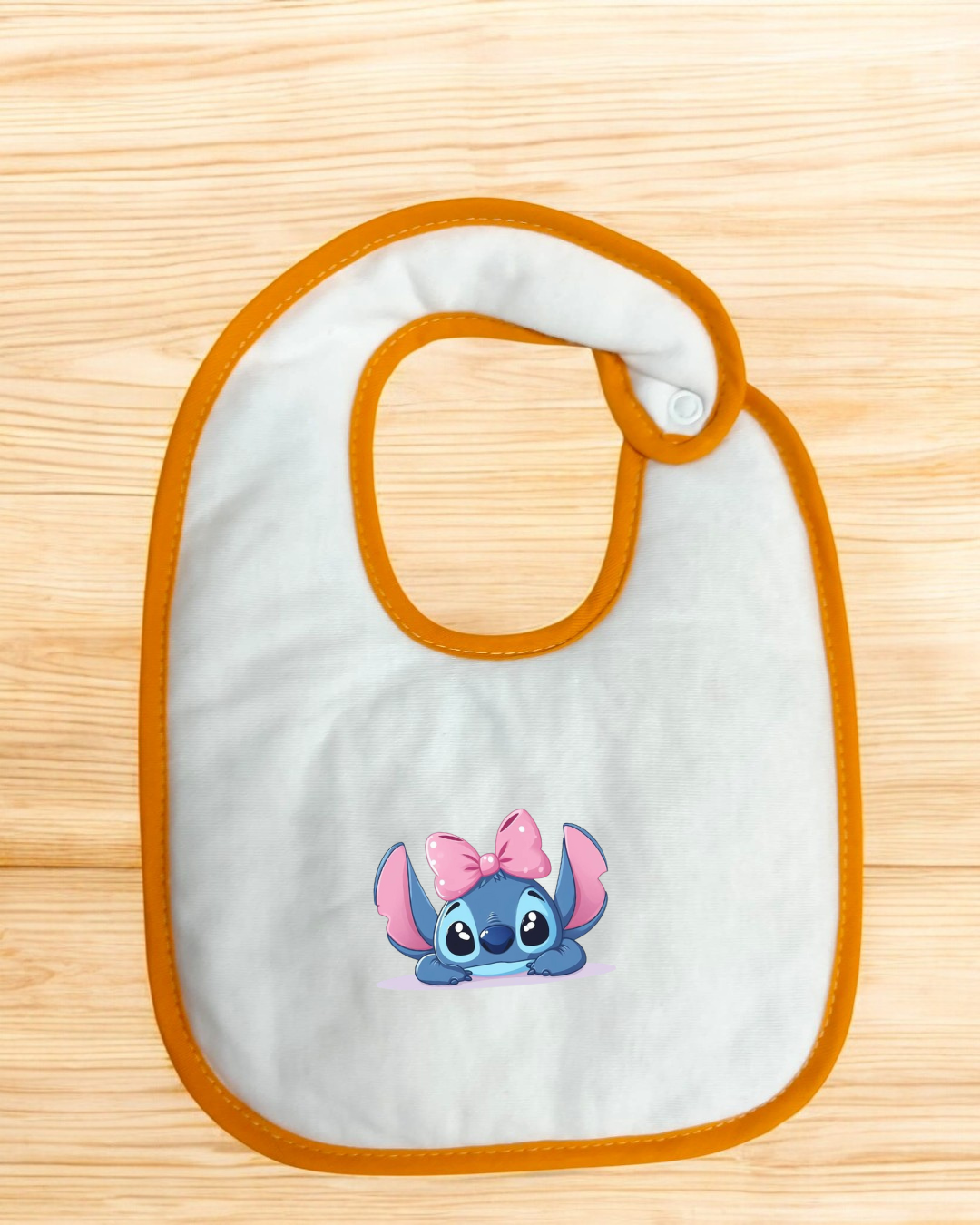 Babete branco com bordas laranja e personagem azul com laço rosa