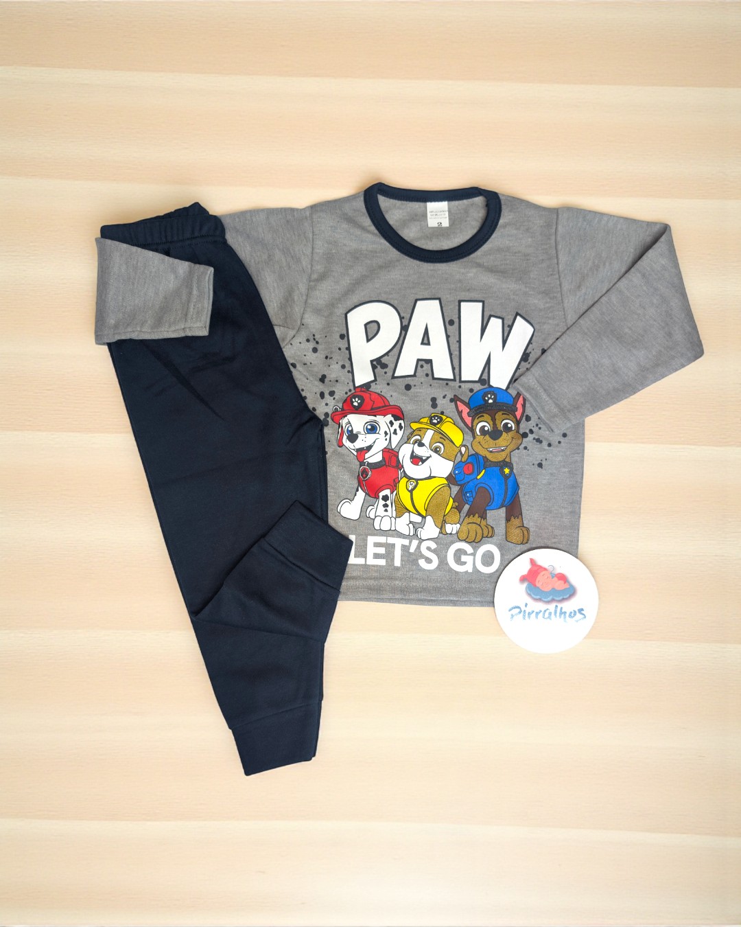Roupa infantil com camisa cinzenta e calças pretas, desenho de cães e texto
