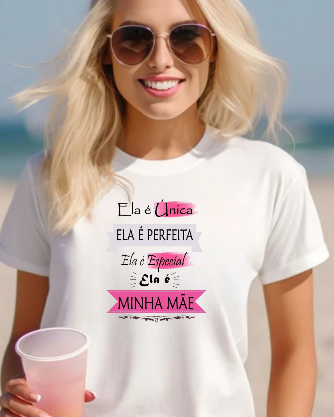 Mulher loira com t-shirt branca com texto para mãe, óculos de sol e copo plástico rosado, cenário de praia
