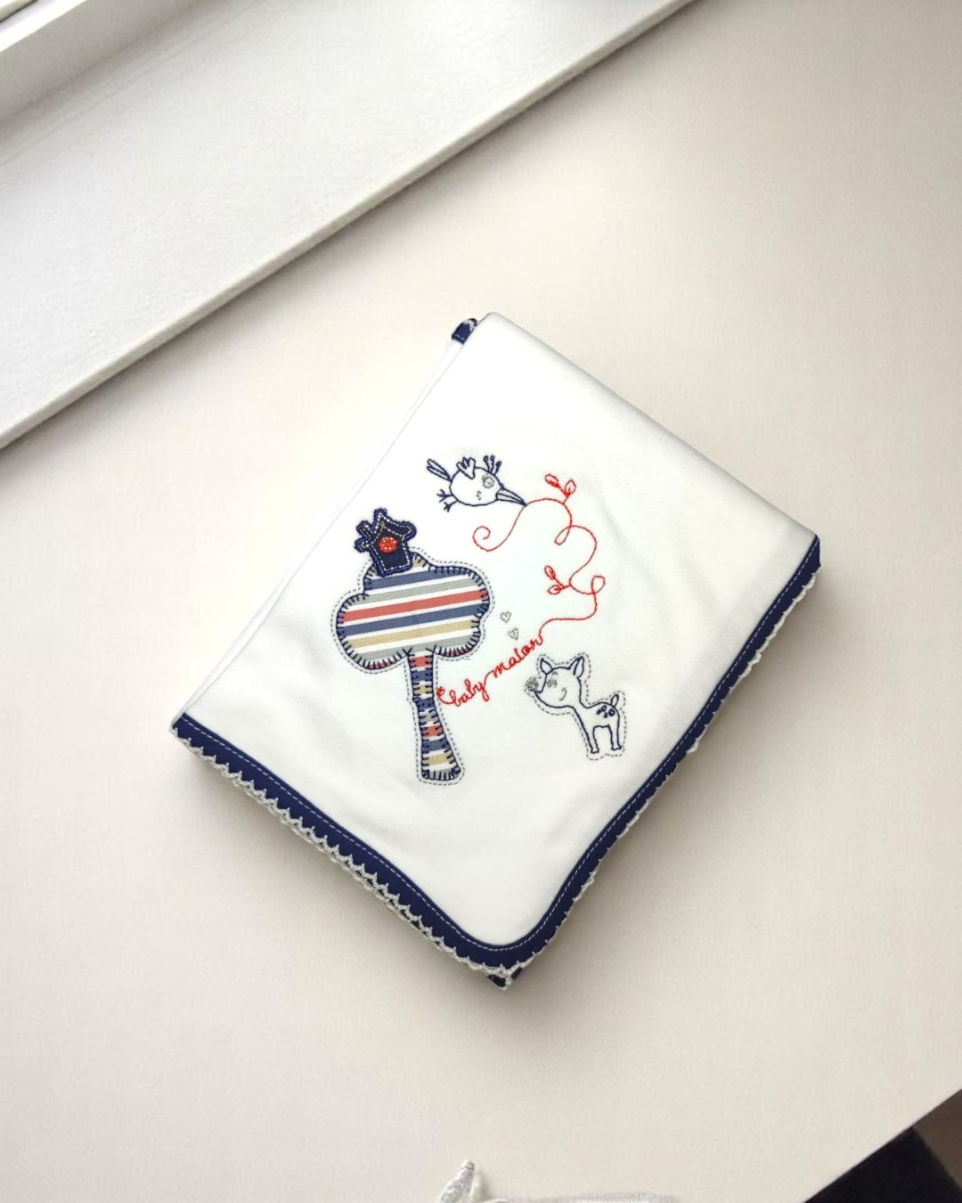 Manta branca para bebé com bordado colorido e borda azul