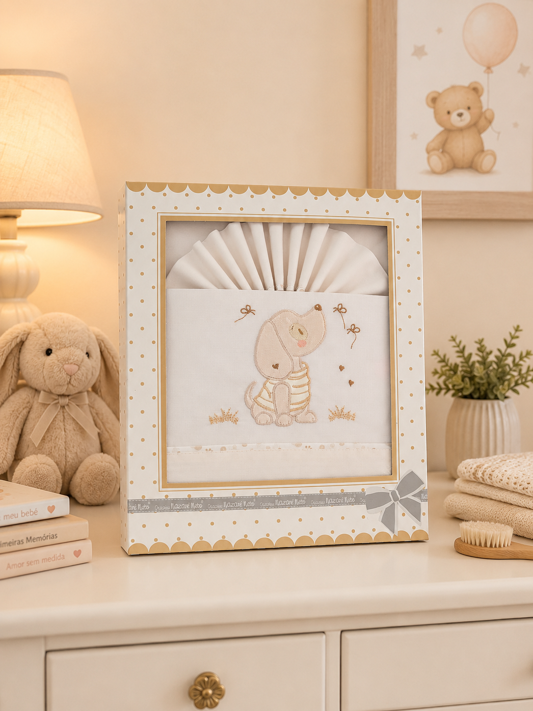 Conjunto de roupa de bebé branco com bordado de cachorro em caixa decorativa sobre móvel creme
