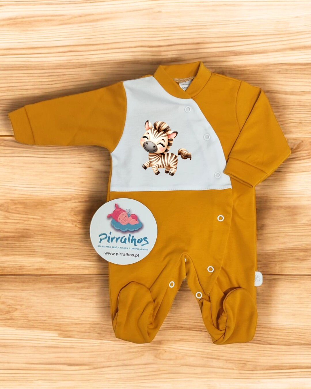 Pijama mostarda com estampa de zebra para bebé em fundo de madeira