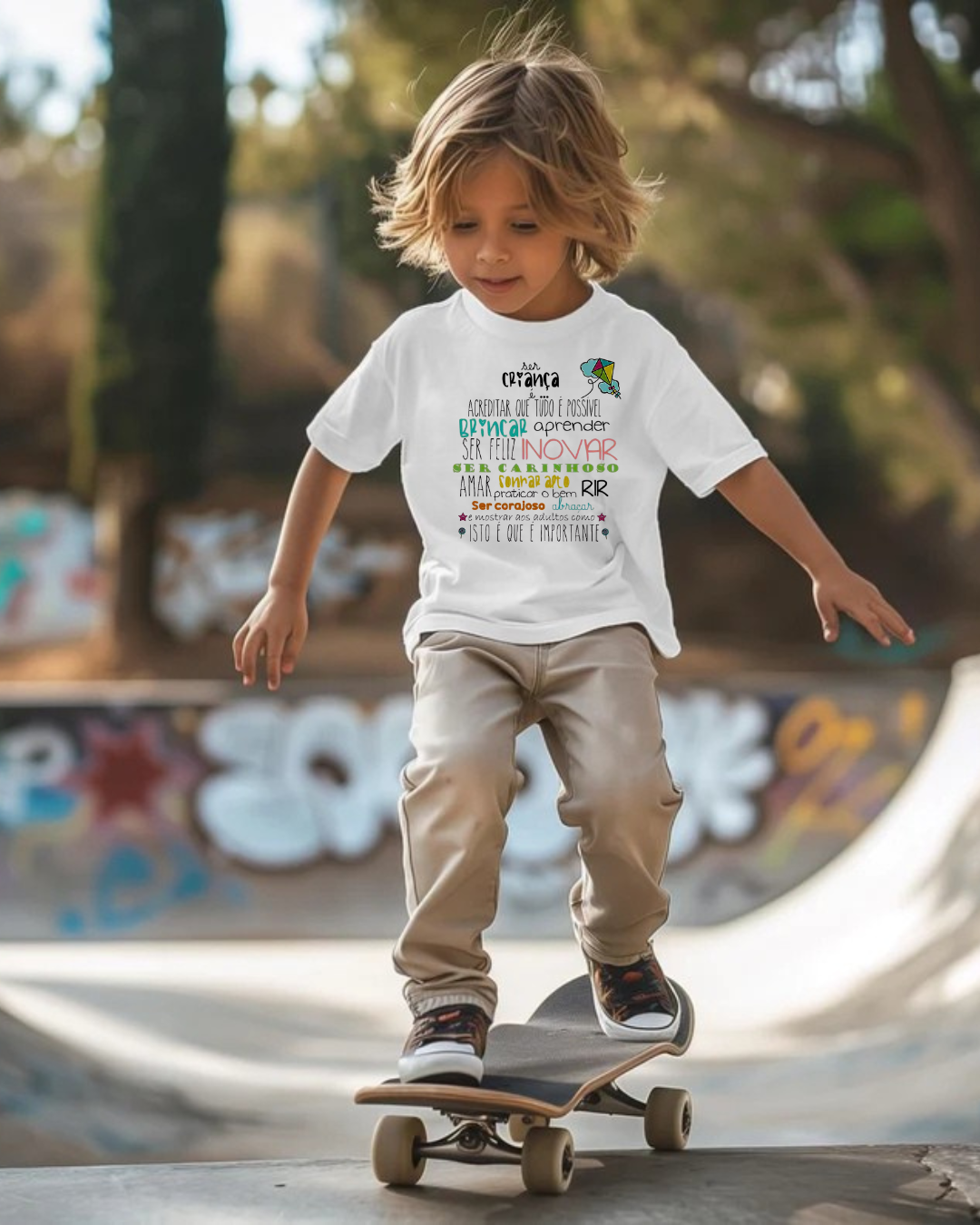 Criança em skate com camisola branca estampada e calças bege em parque de skate.