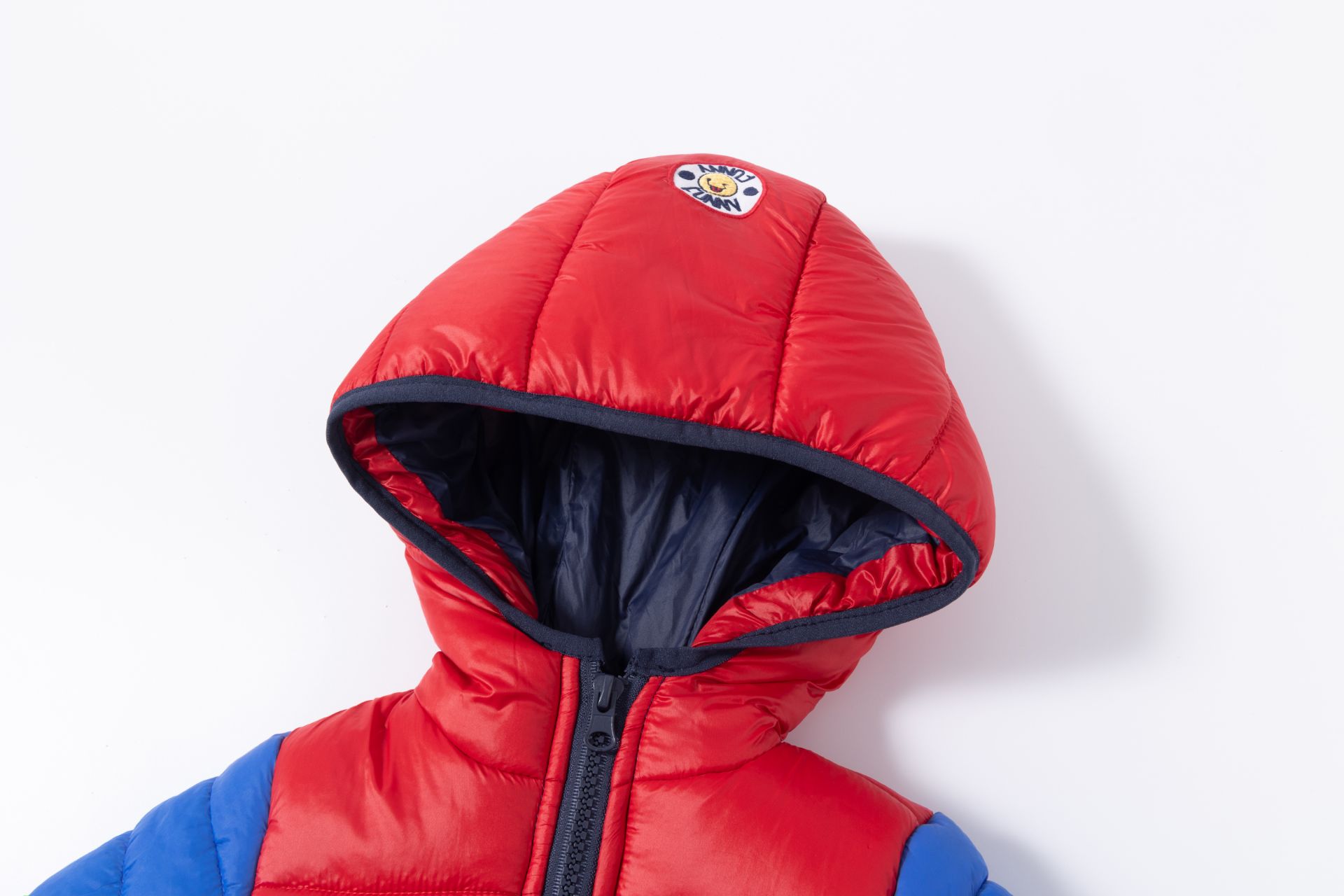 Casaco de criança acolchoado vermelho e azul com capuz e fecho de correr.