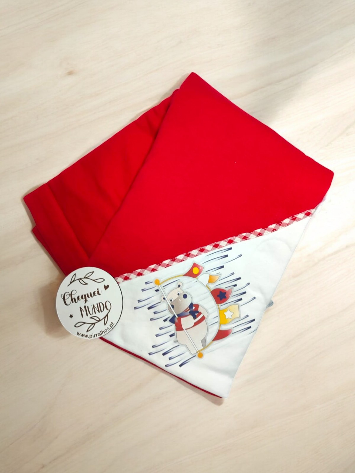 Manta infantil vermelha com padrão de animais e etiqueta redonda