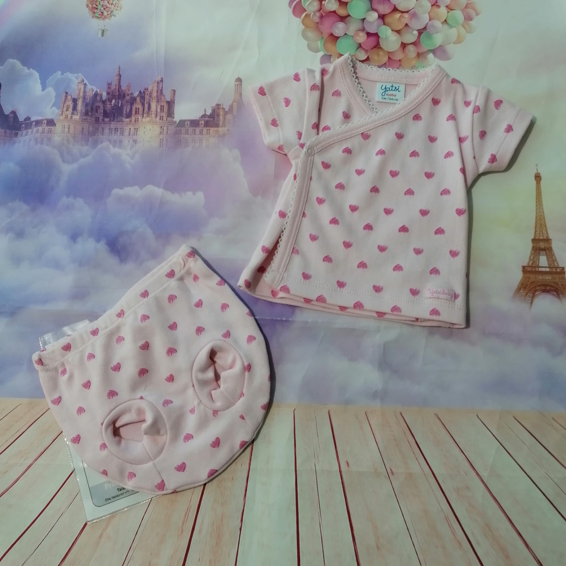 Conjunto de roupa de bebé cor-de-rosa com corações em fundo de castelo e Torre Eiffel